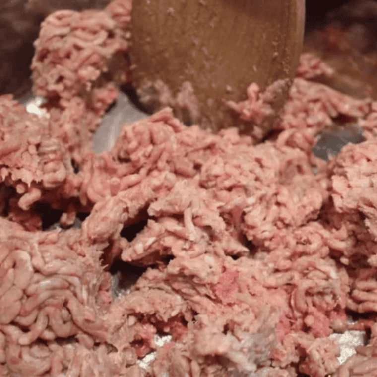 Ground beef and diced yellow onion browning together in Instant Pot inner pot on sauté setting