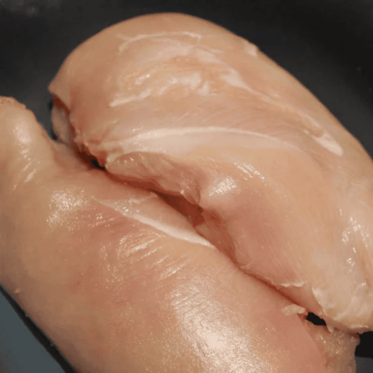 Seasoned chicken breasts searing in olive oil on the Sauté setting of an Instant Pot