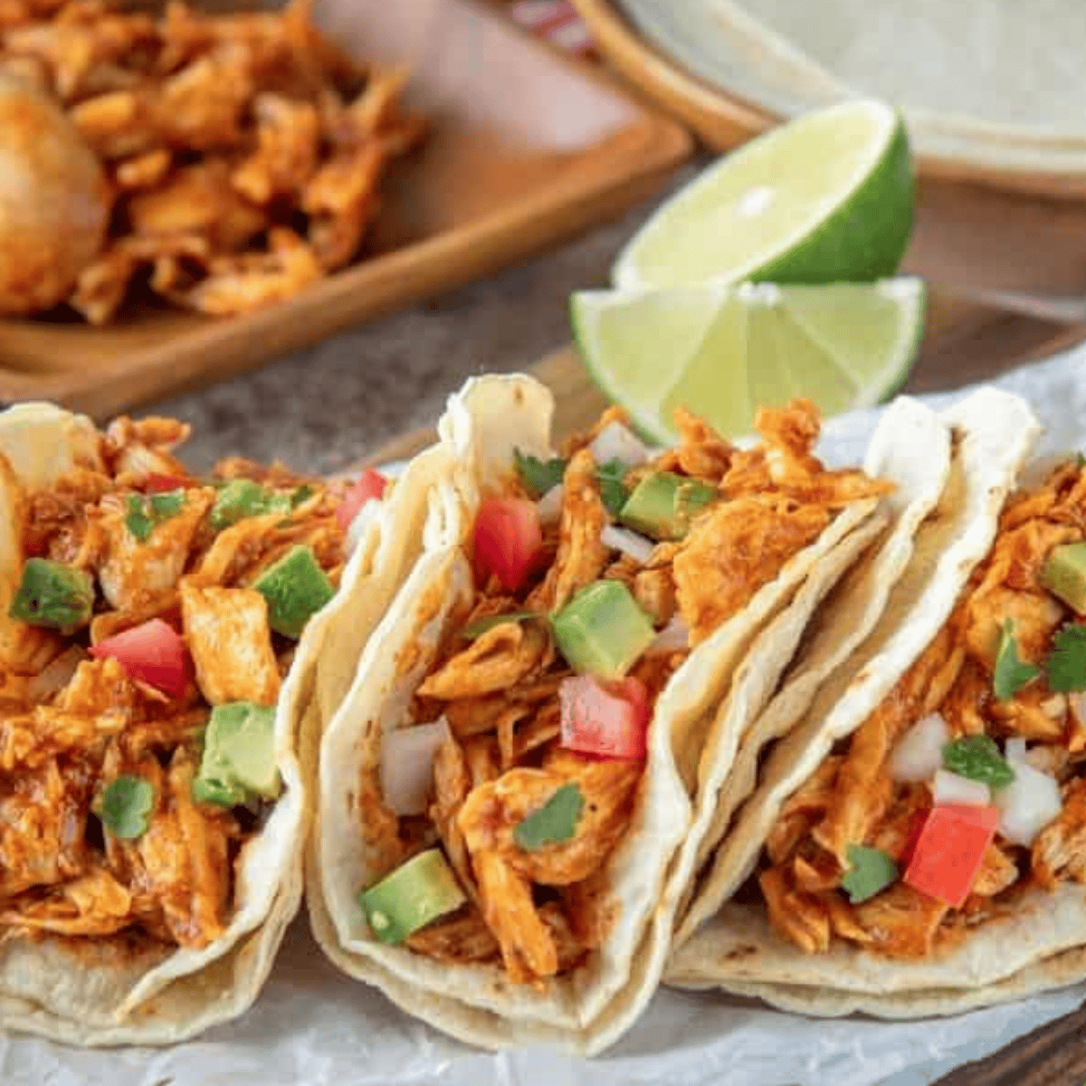 Instant Pot salsa chicken piled into a soft flour tortilla with cheese, cilantro, and lime