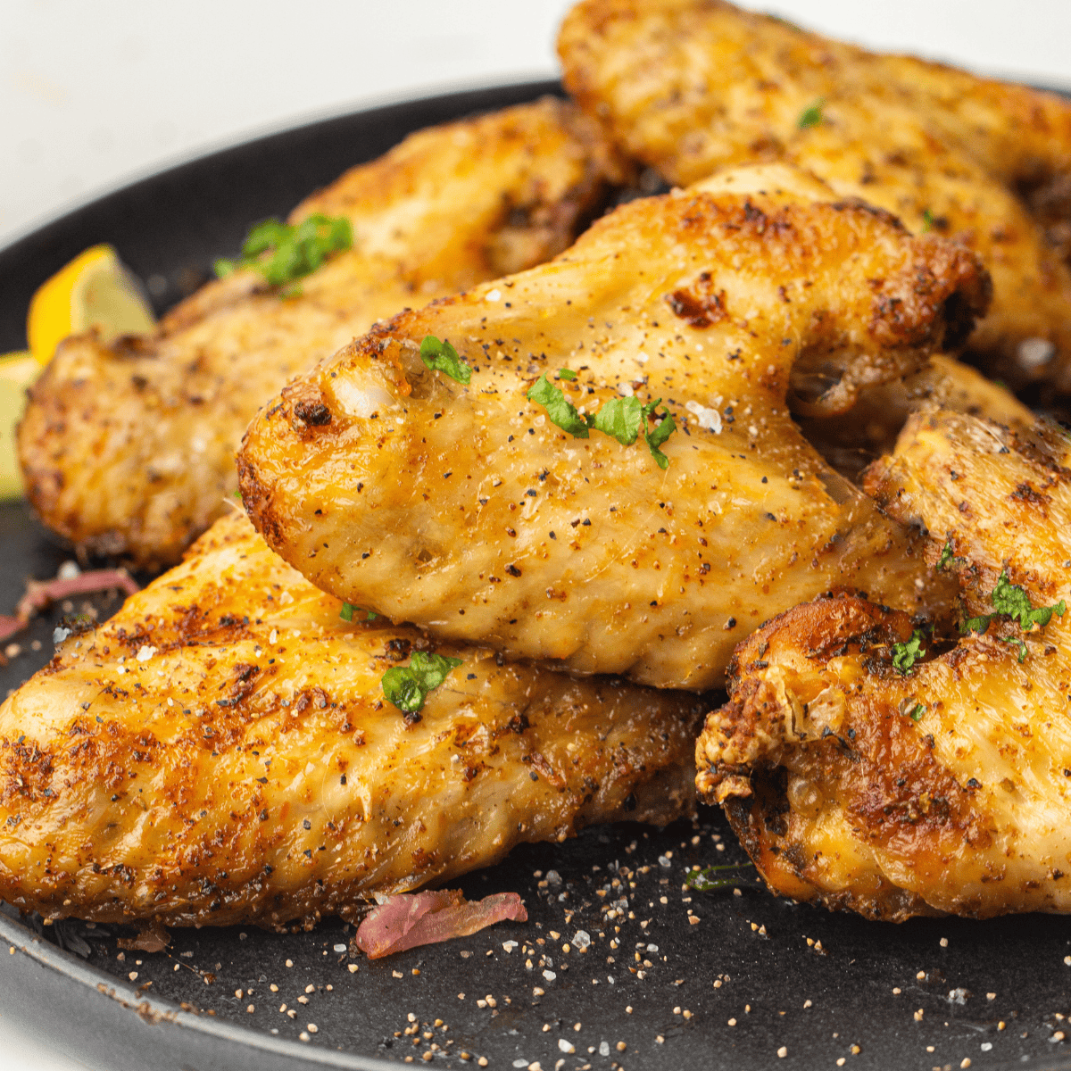 Golden crispy Ninja Crispi chicken wings in glass air fryer container