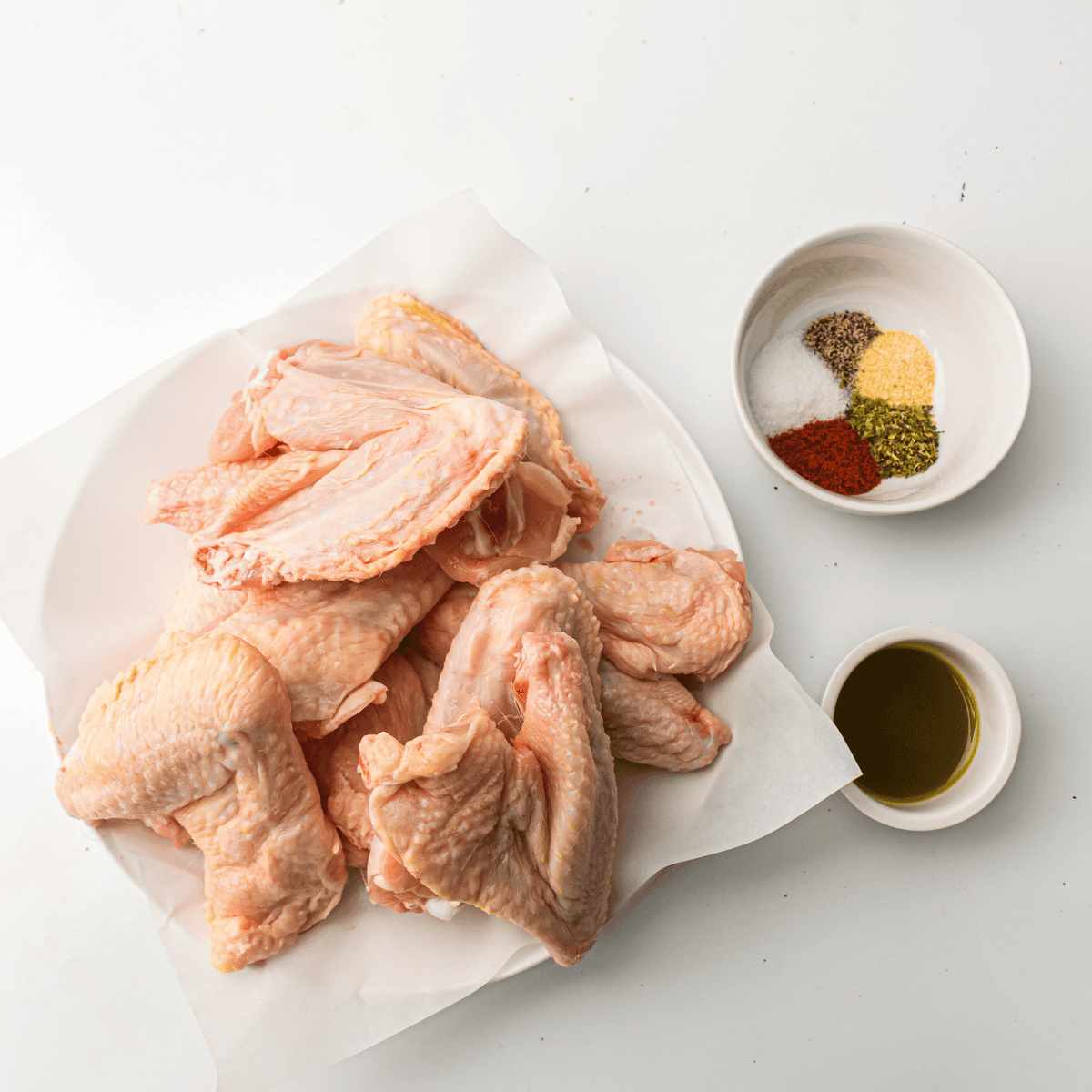Ingredients for Ninja Crispi chicken wings including raw wings, oil, baking powder, and seasonings