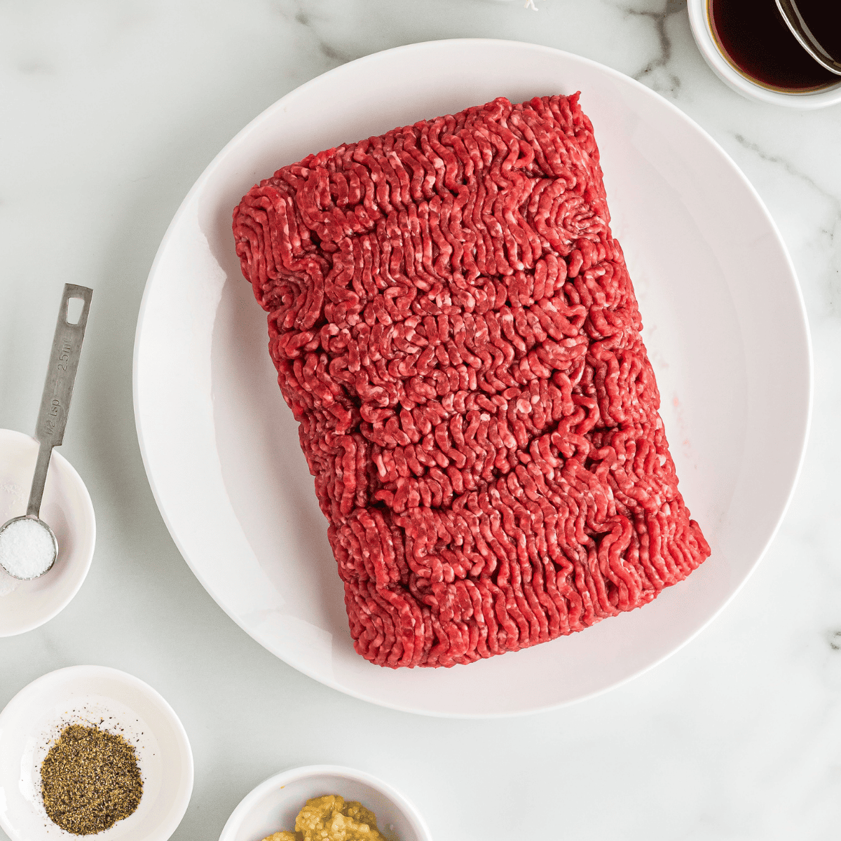 Ground lamb and gyro seasoning ingredients laid out on a counter.
