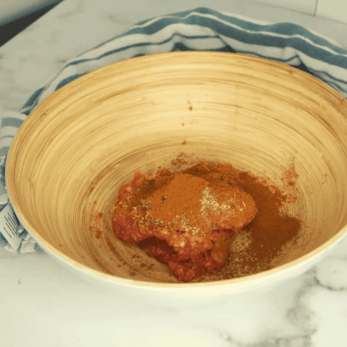 Ground lamb and gyro spices being mixed in a glass bowl