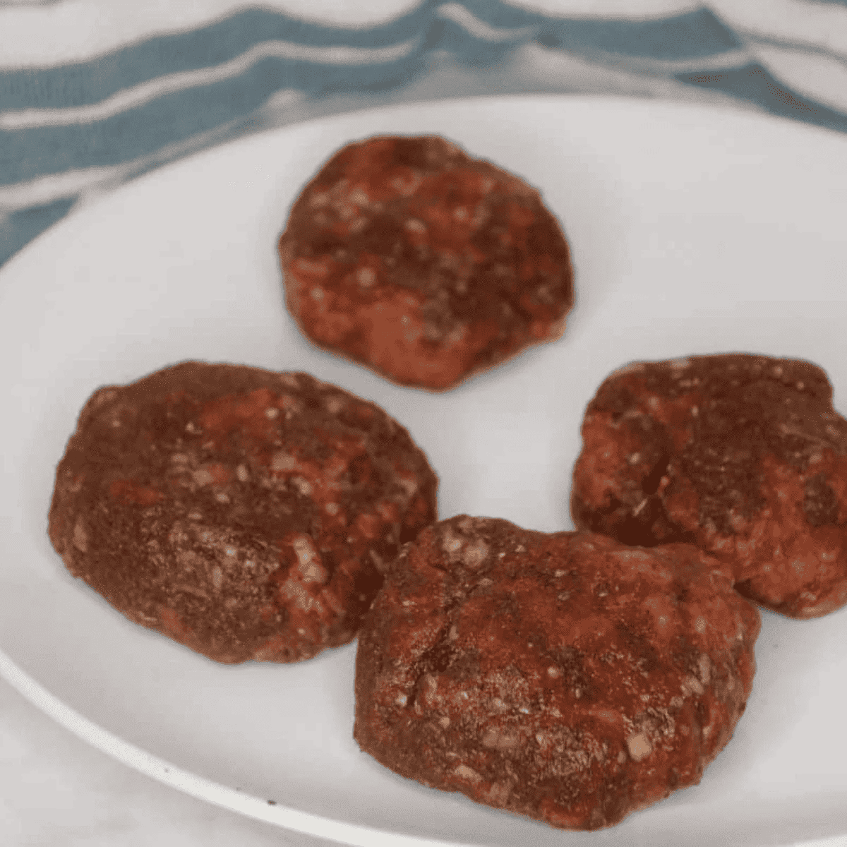 Raw seasoned lamb gyro patties shaped on a tray before chilling.