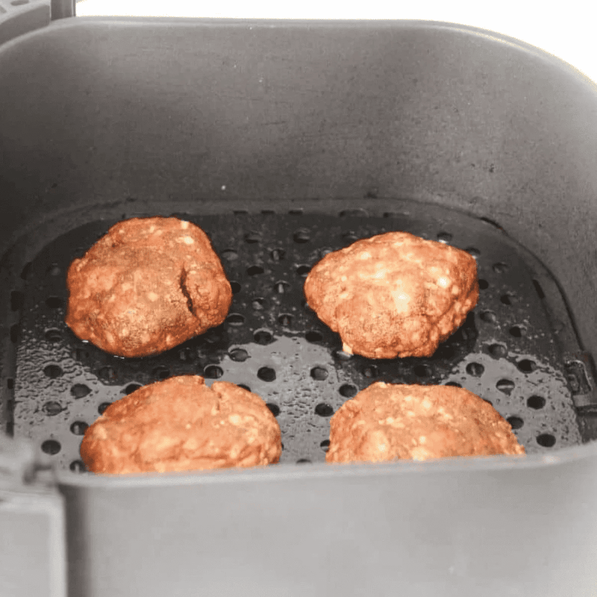 Lamb gyro patties cooking in a single layer in the air fryer basket