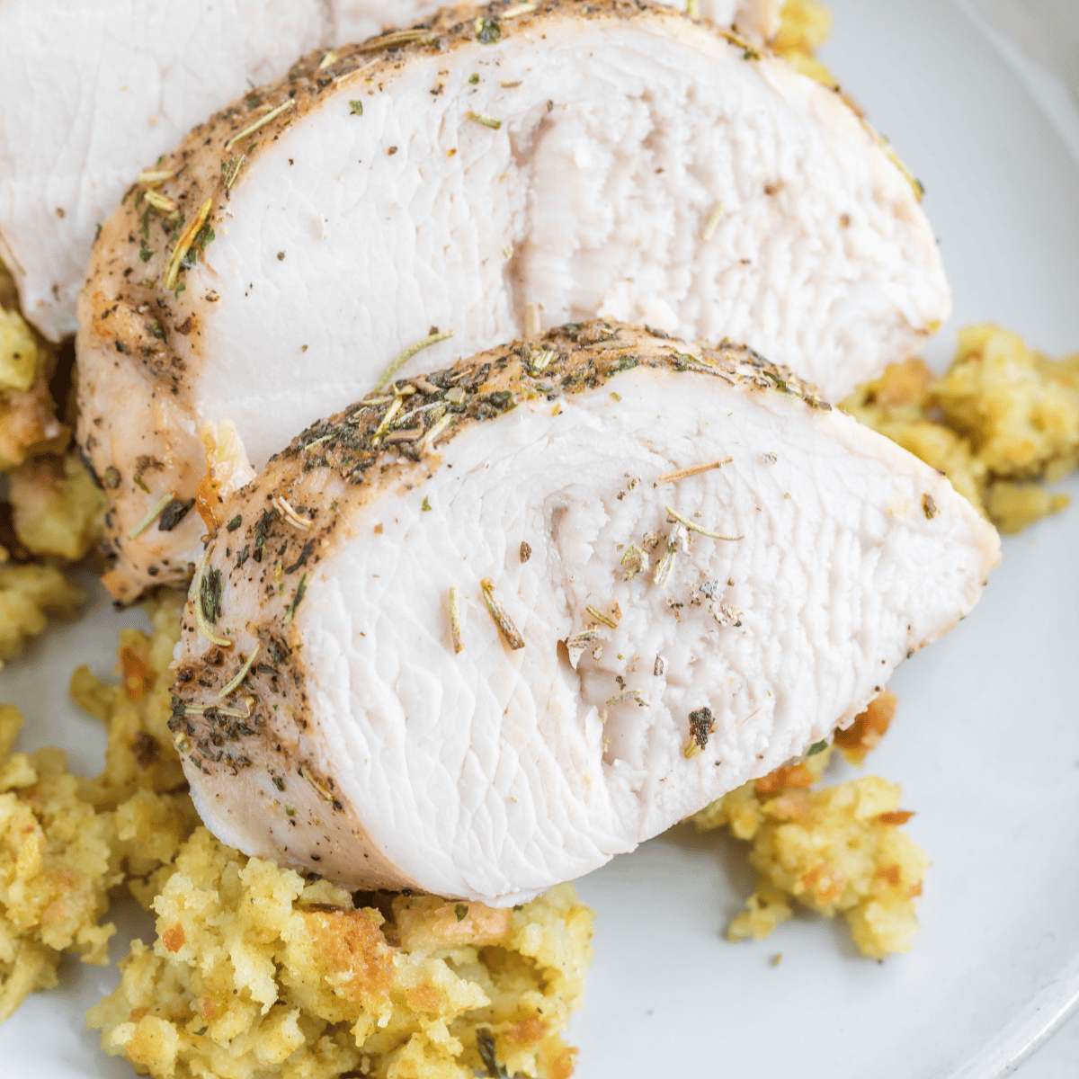 Golden-brown air fryer turkey tenderloin sliced on a plate, garnished with herbs and ready to serve.