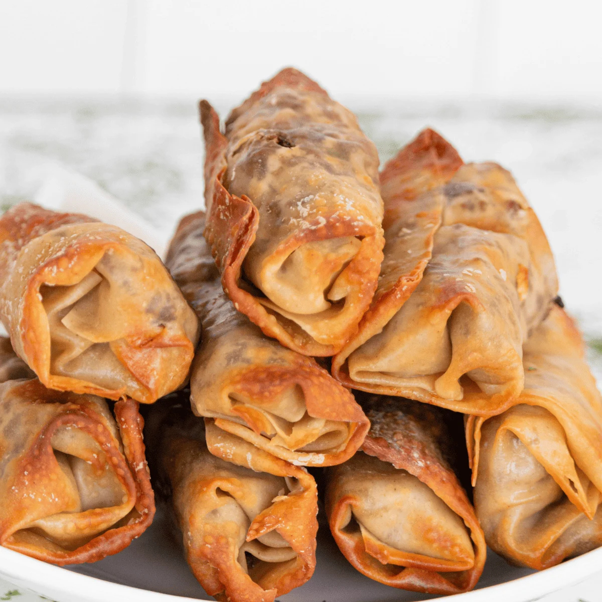 Plate of copycat TGI Fridays Philly cheesesteak egg rolls with a bowl of creamy horseradish sauce
