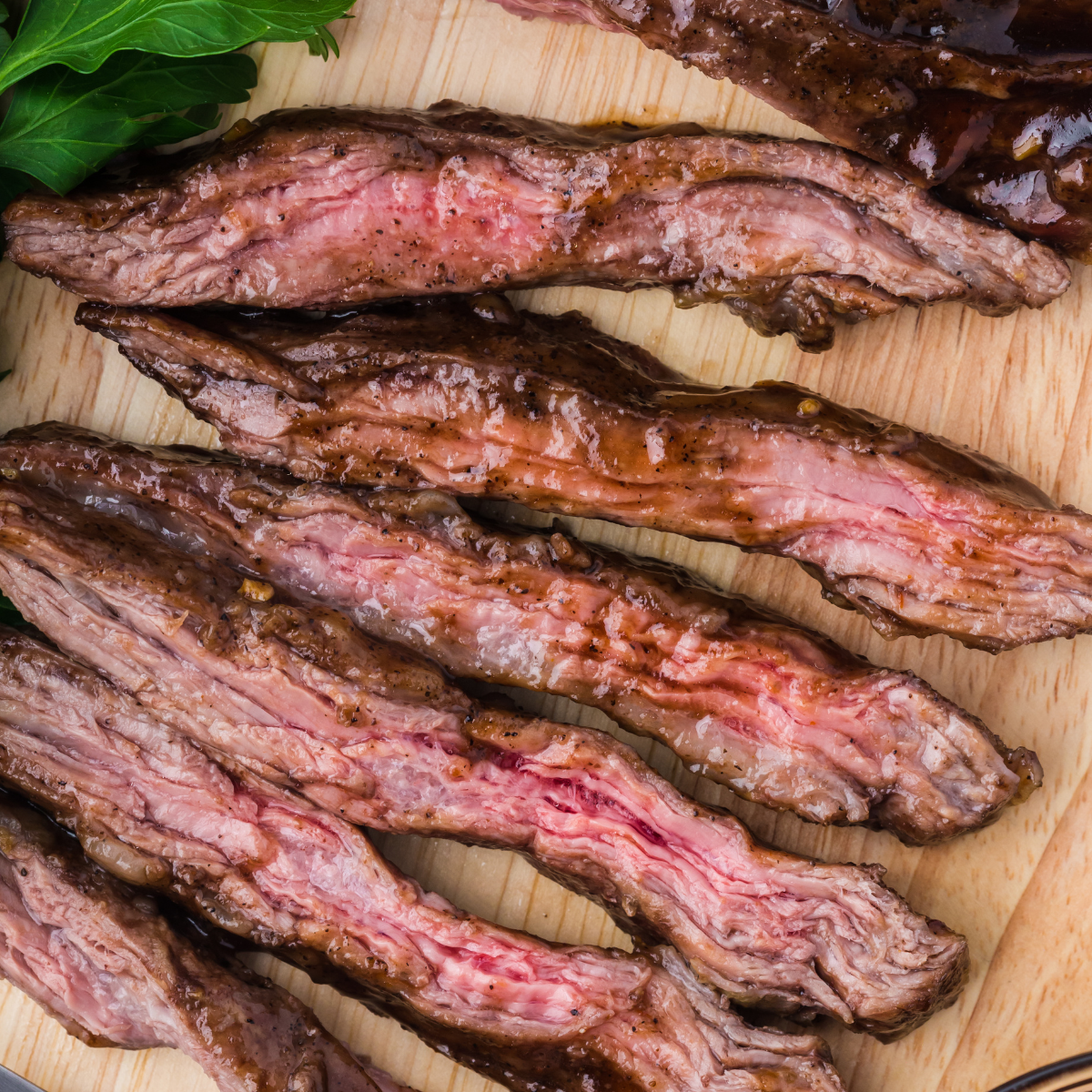 Juicy air fryer skirt steak sliced and served on plate with browned edges and fresh herbs on top