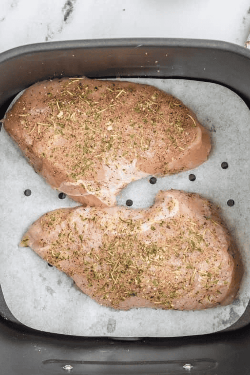 Seasoned turkey tenderloin placed in preheated air fryer basket, cooking to juicy perfection.