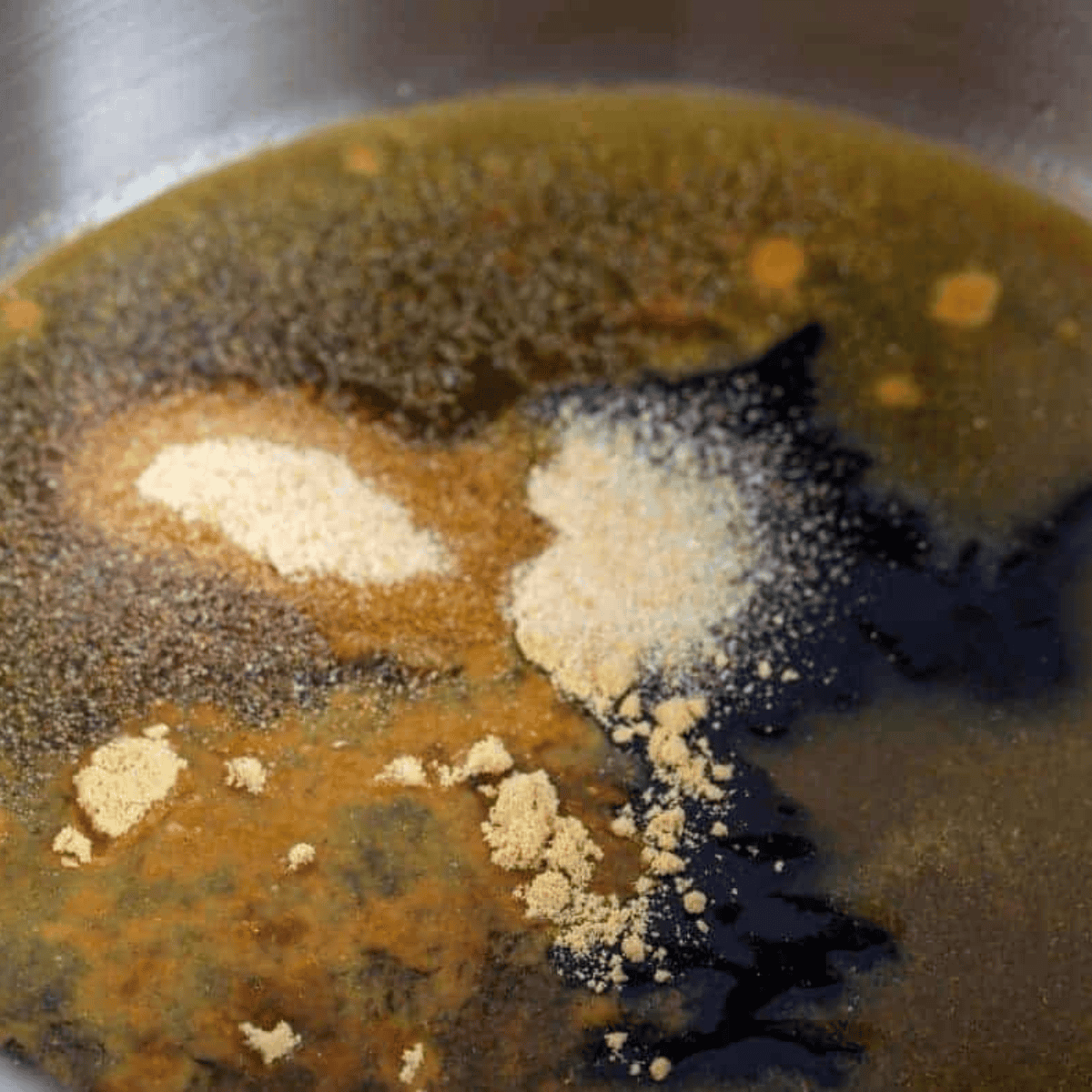 Sesame chicken sauce simmering in a saucepan as cornstarch mixture thickens the glaze.