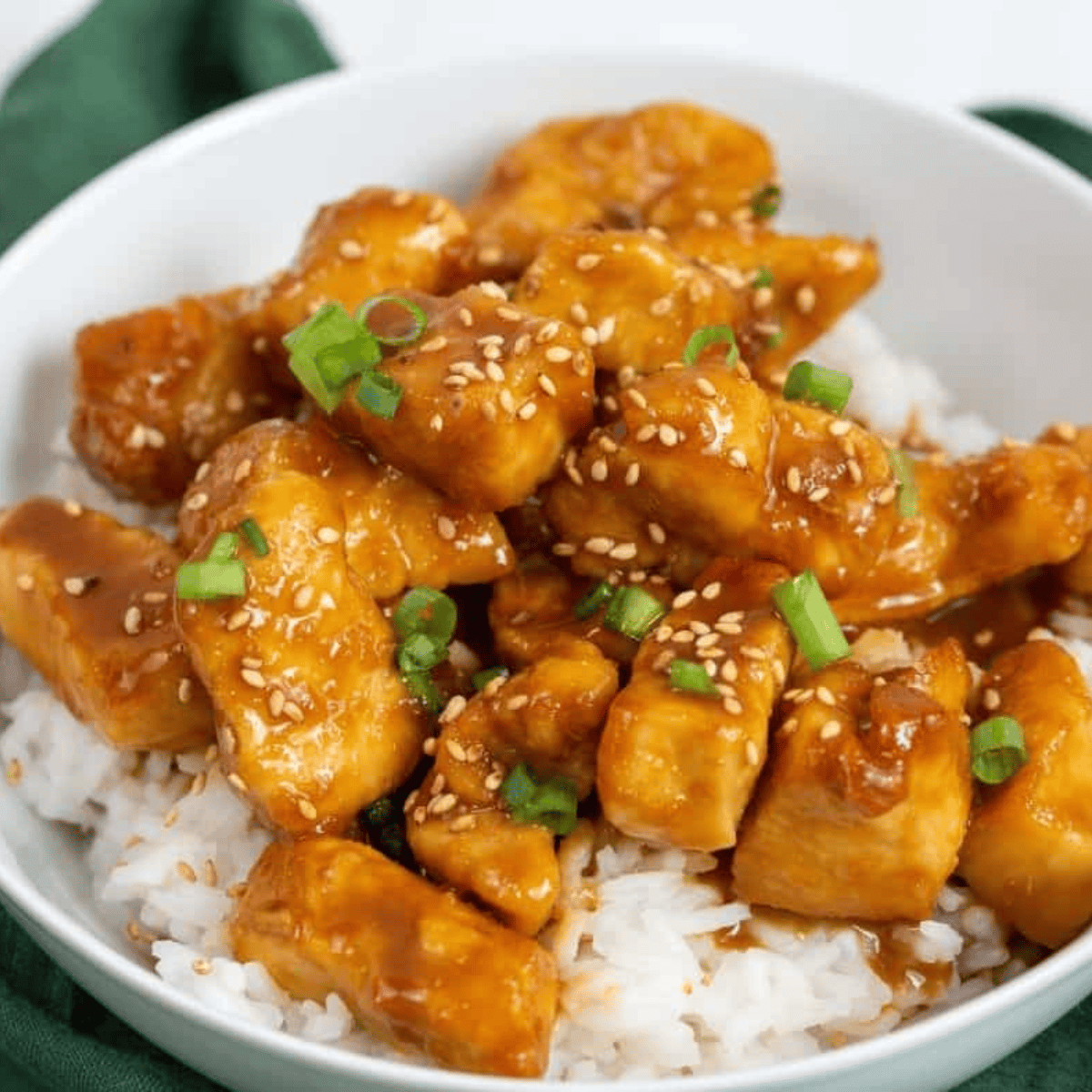 Crispy sesame chicken coated in glossy sauce, garnished with sesame seeds on a plate.