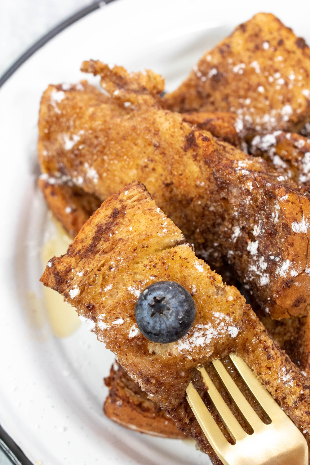 Basket of air fryer French toast sticks with syrup and fresh berries on table