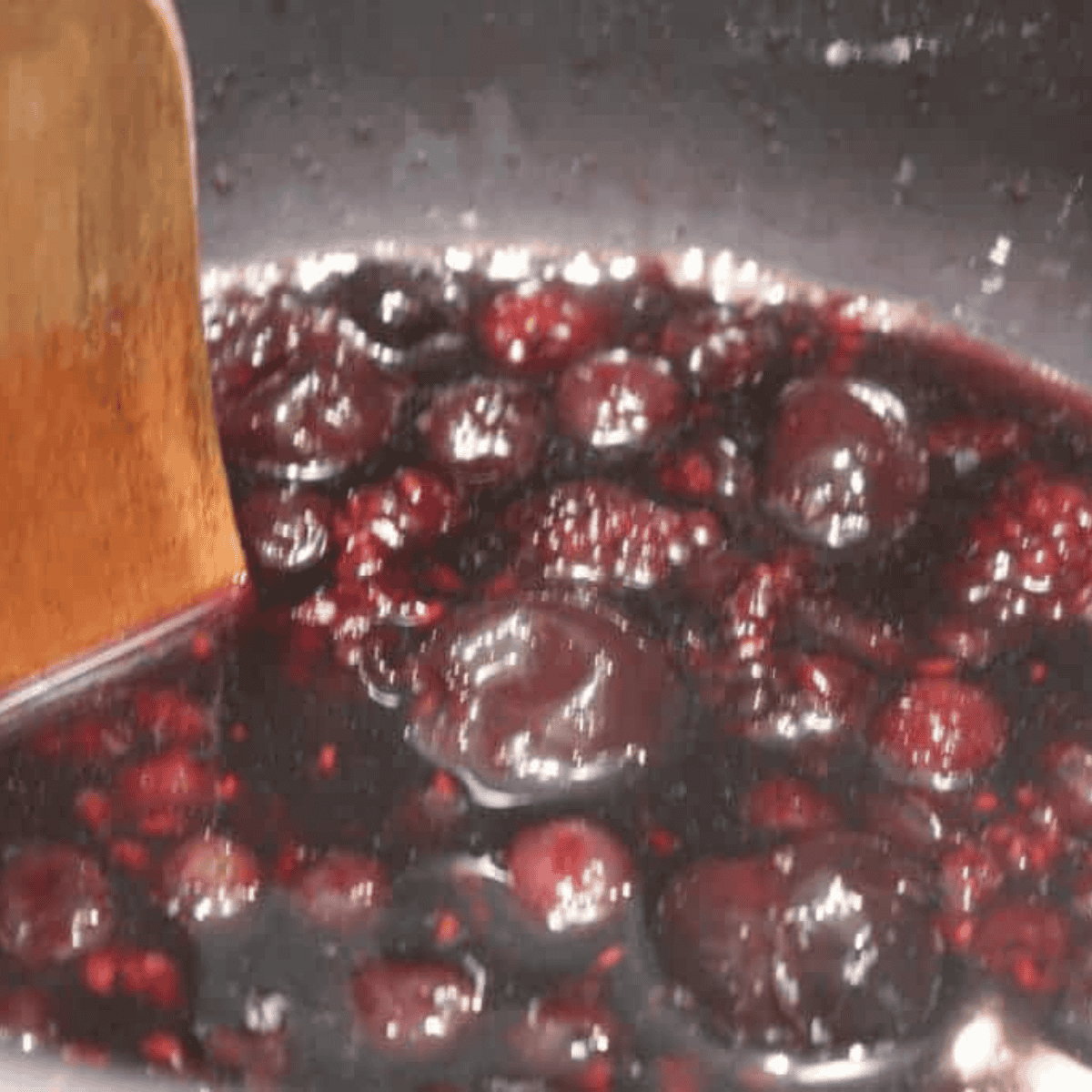 Blending cooked berries into smooth jam with an immersion blender