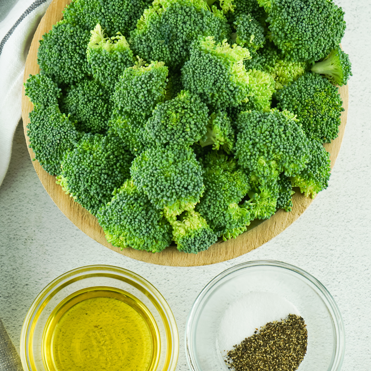 Ingredients for Ninja Crispi broccoli including fresh florets, olive oil, garlic powder, and Parmesan