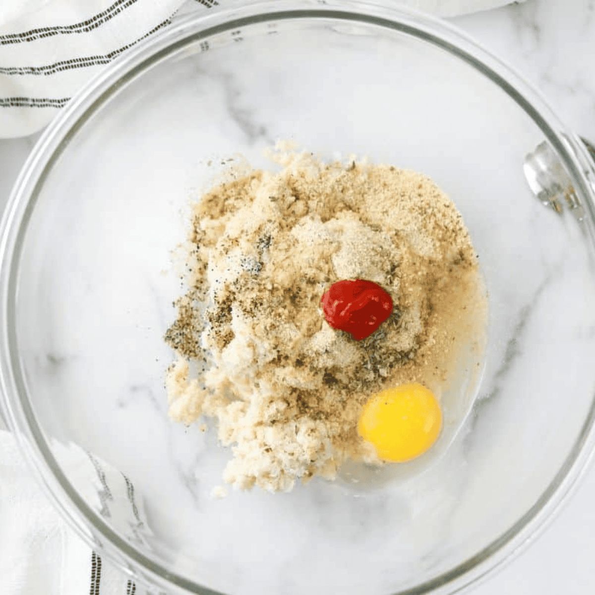 Mixing crab meat, tomato sauce, egg, breadcrumbs, and seasonings in a bowl for Air Fryer Bacon and Crab Rolls.