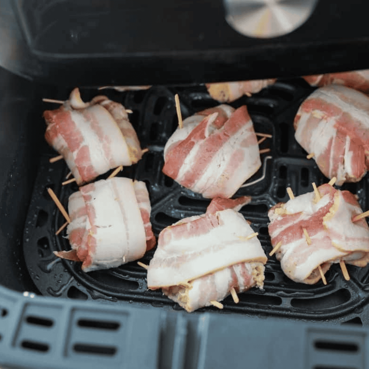 Bacon-wrapped crab rolls in air fryer basket ready to cook at 350°F
