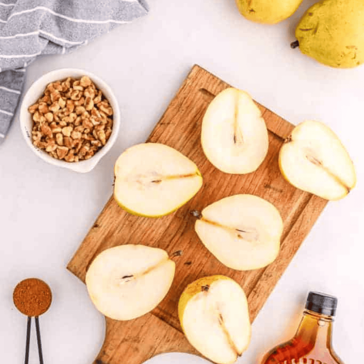Ingredients for Air Fryer Baked Pears including fresh pears, butter, honey, cinnamon, sugar, and chopped nuts arranged on a countertop