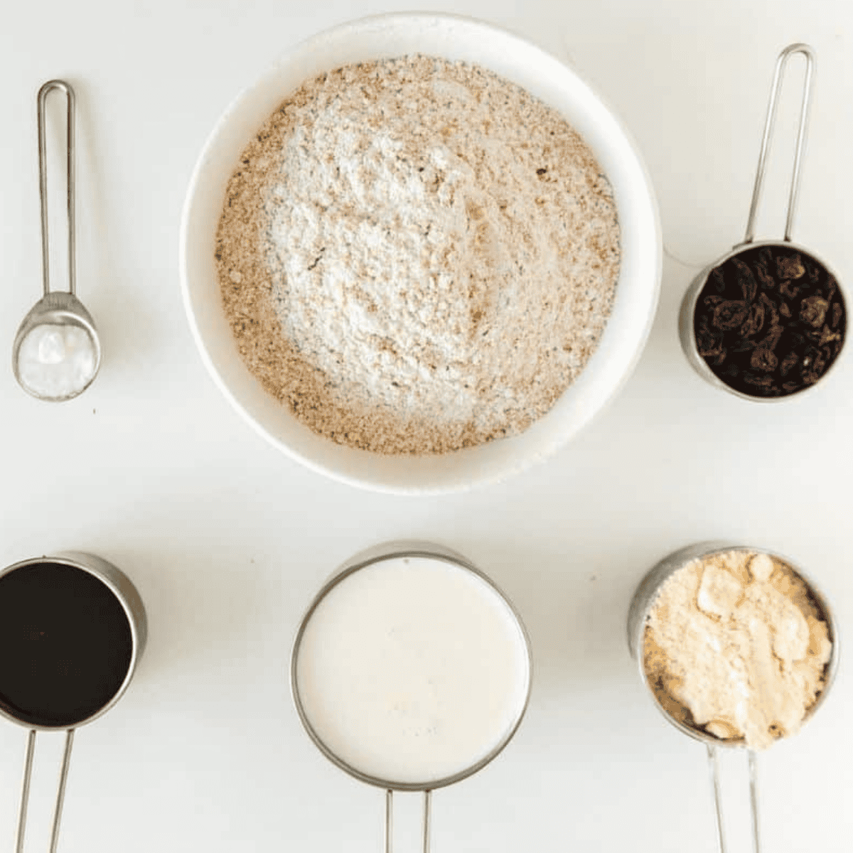 Ingredients for air fryer Boston brown bread: whole wheat flour, cornmeal, baking soda, salt, buttermilk, molasses, and raisins in bowls