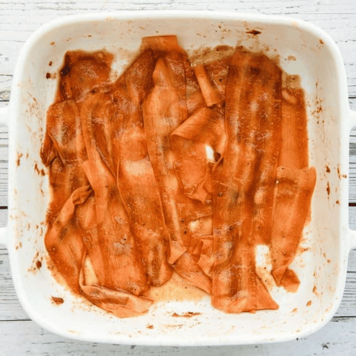 Shaving carrots into thin strips with a vegetable peeler for carrot bacon