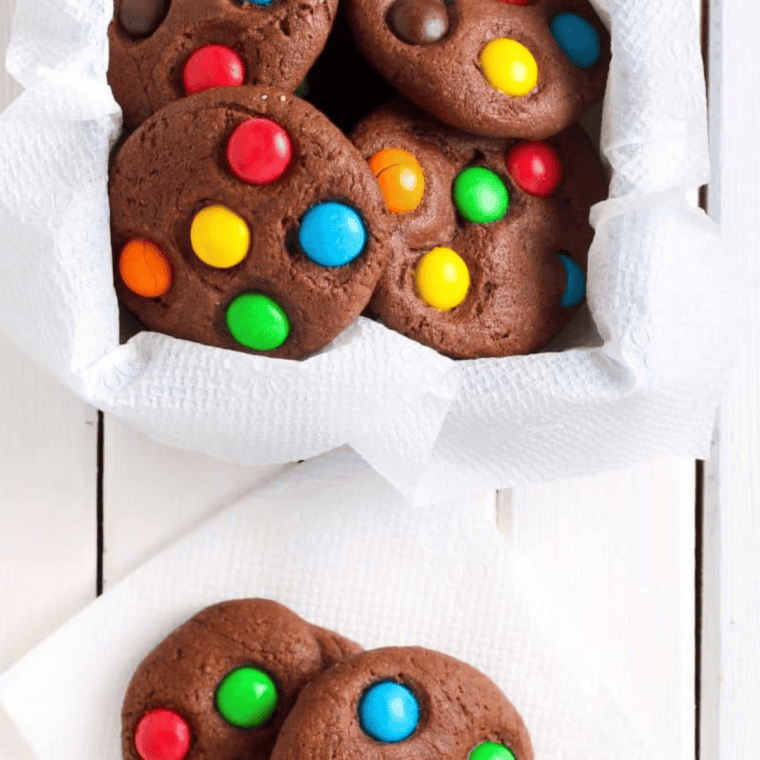 Chewy air fryer monster cookies stacked on a cooling rack with chocolate chips and candy pieces.