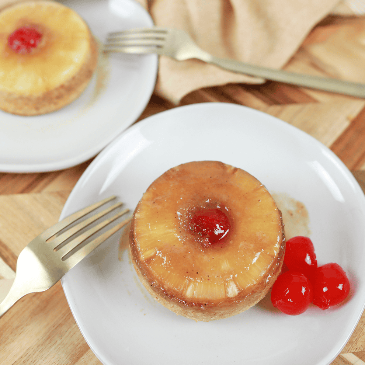 Air fryer pineapple upside-down cake for two, with caramelized pineapple slices and cherries on top.
