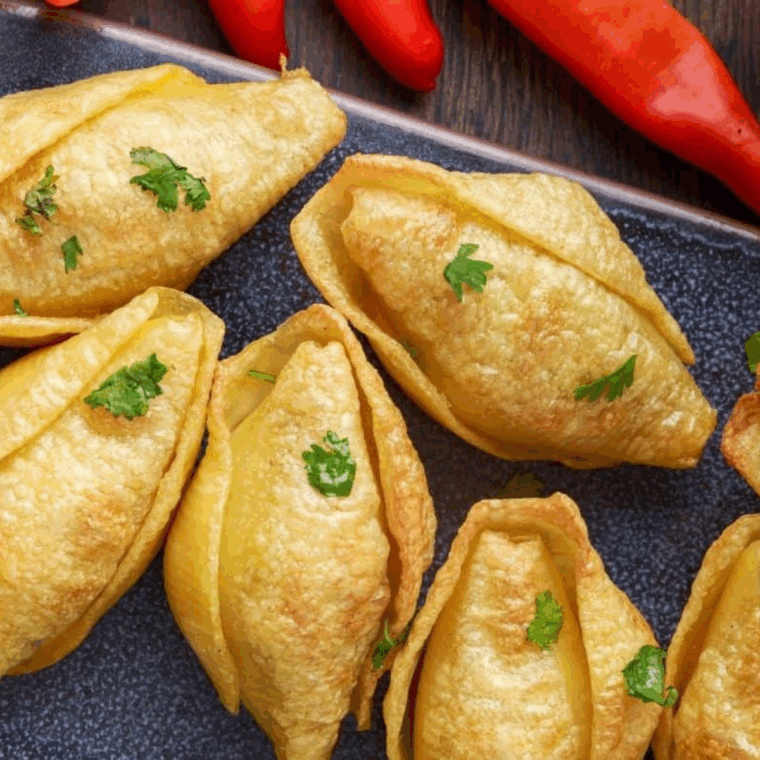 Air fryer taco stuffed pasta shells filled with pork carnitas and cheddar cheese, golden brown and ready to serve on a plate.