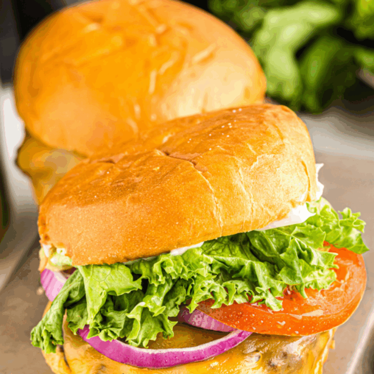 Close-up of a homemade Dairy Queen Flamethrower Burger with jalapeño sauce, melted cheese, and fresh toppings on a toasted bun.