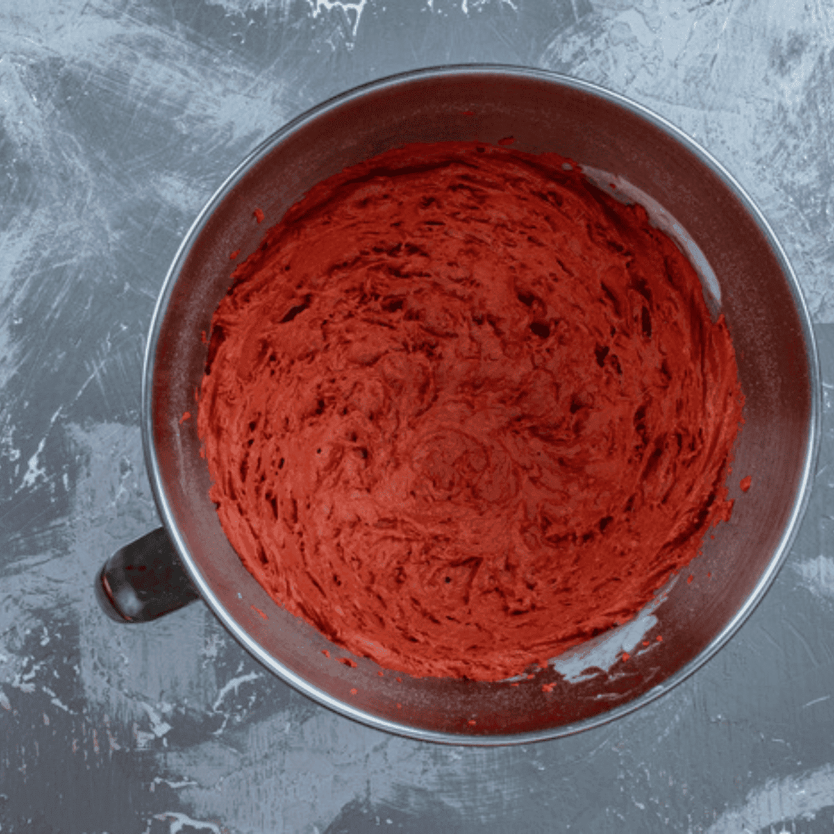 Mixing red velvet cake mix, flour, cold butter, and milk in a large bowl to form scone dough for a flaky texture.