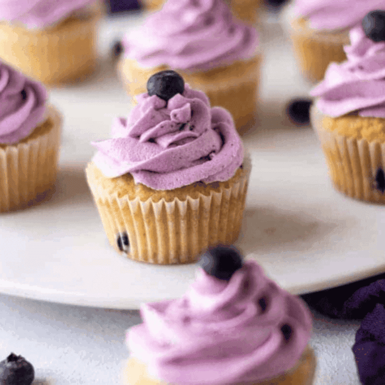 Air fryer blueberry cupcakes in paper liners, golden and fluffy, with fresh blueberries visible on top.