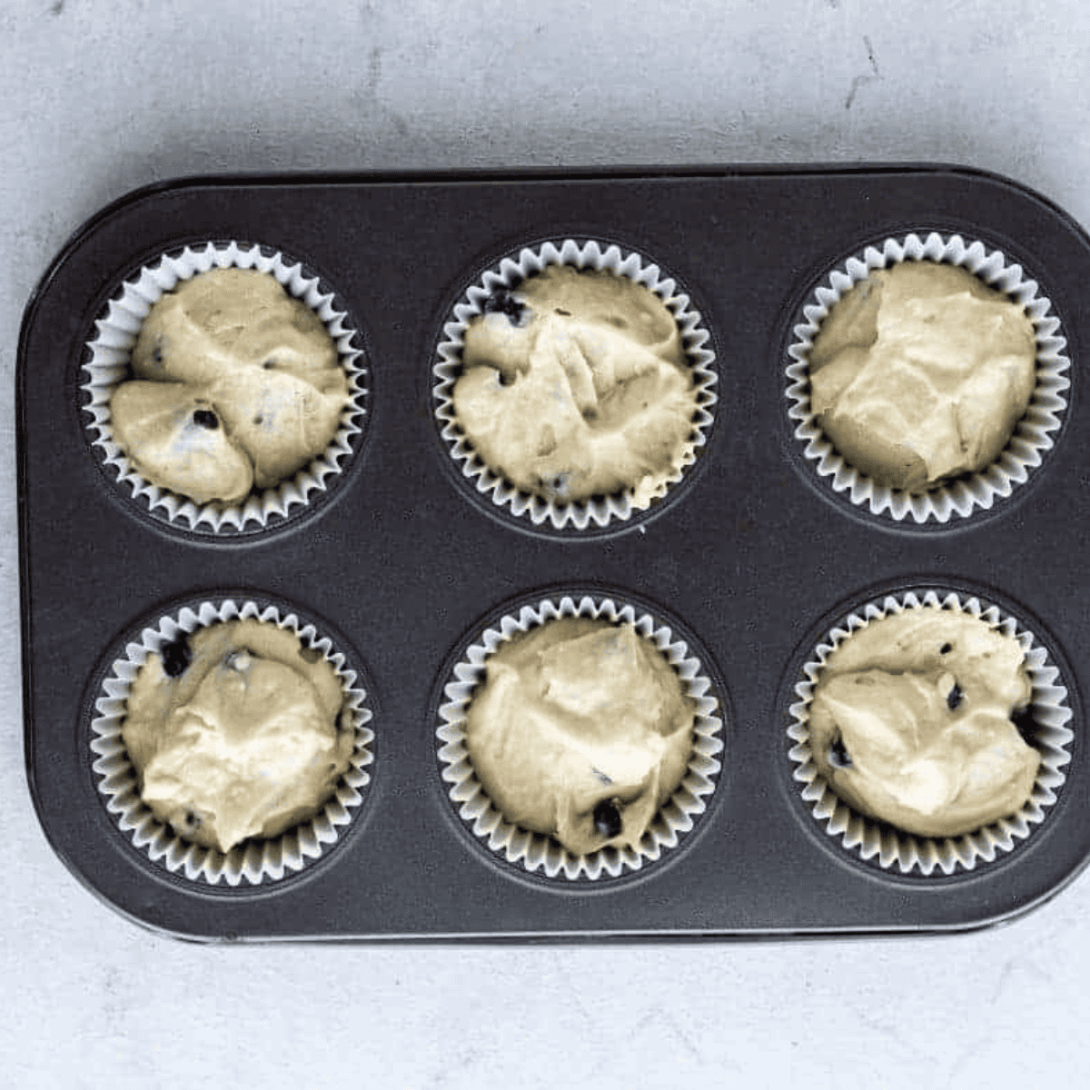 Cupcake liners filled three-quarters with blueberry batter, air fried at 320°F until toothpick comes out clean, then cooled before frosting.