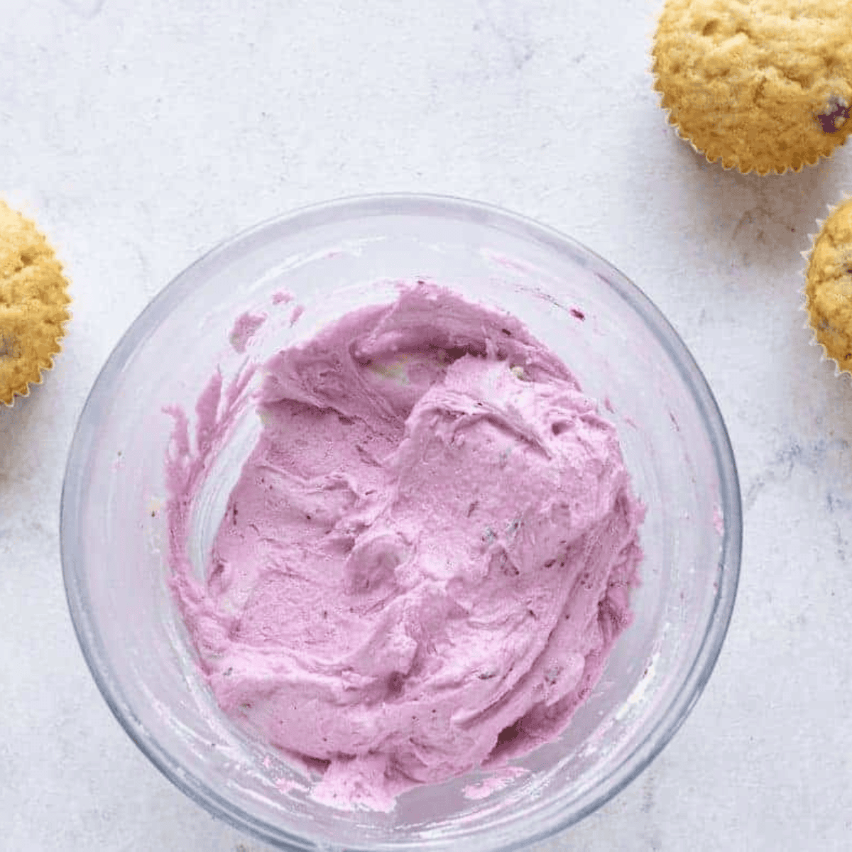 Mixing pureed blueberries into frosting and decorating blueberry cupcakes with the finished icing.