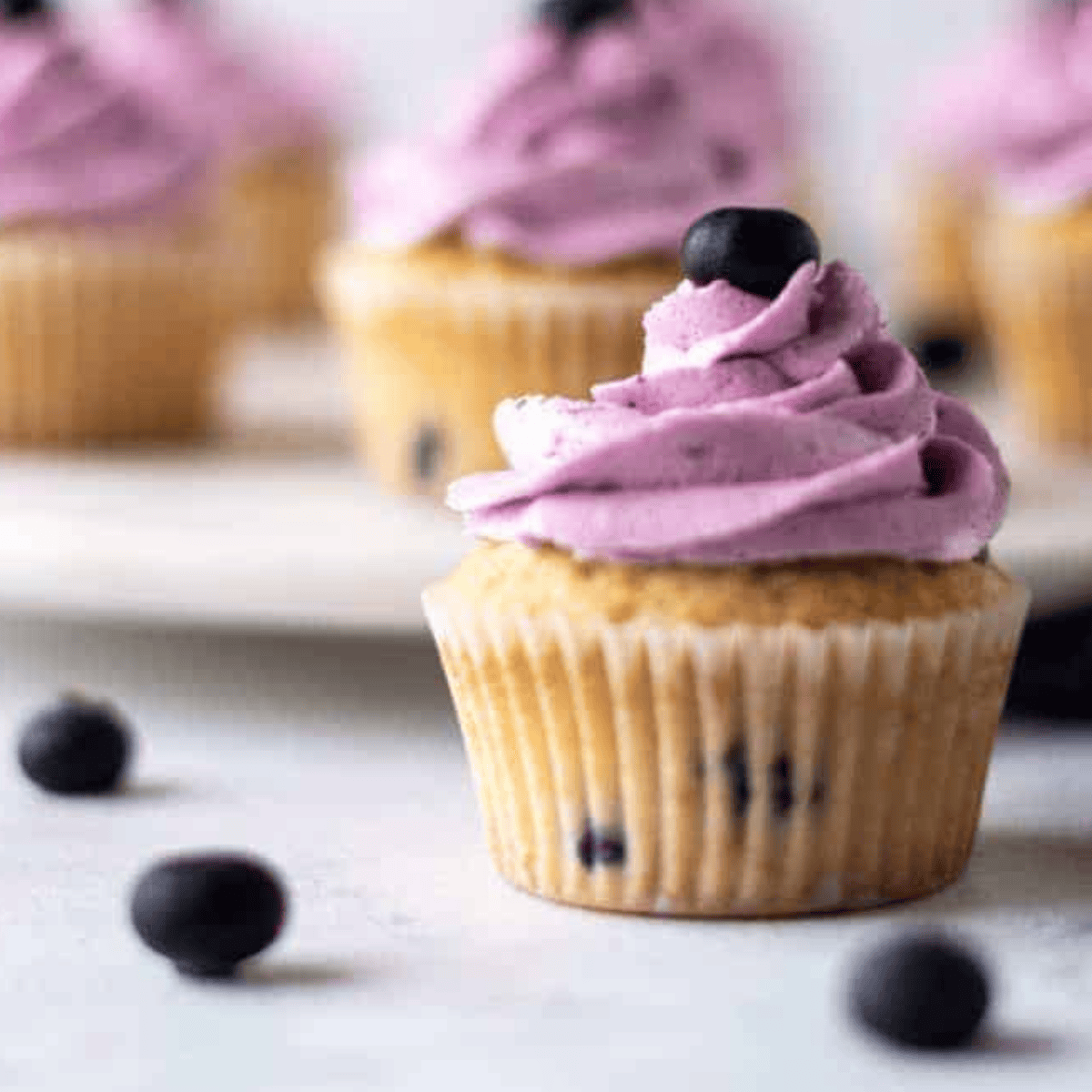 Air fryer blueberry cupcakes in paper liners, golden and fluffy, topped with blueberry frosting.