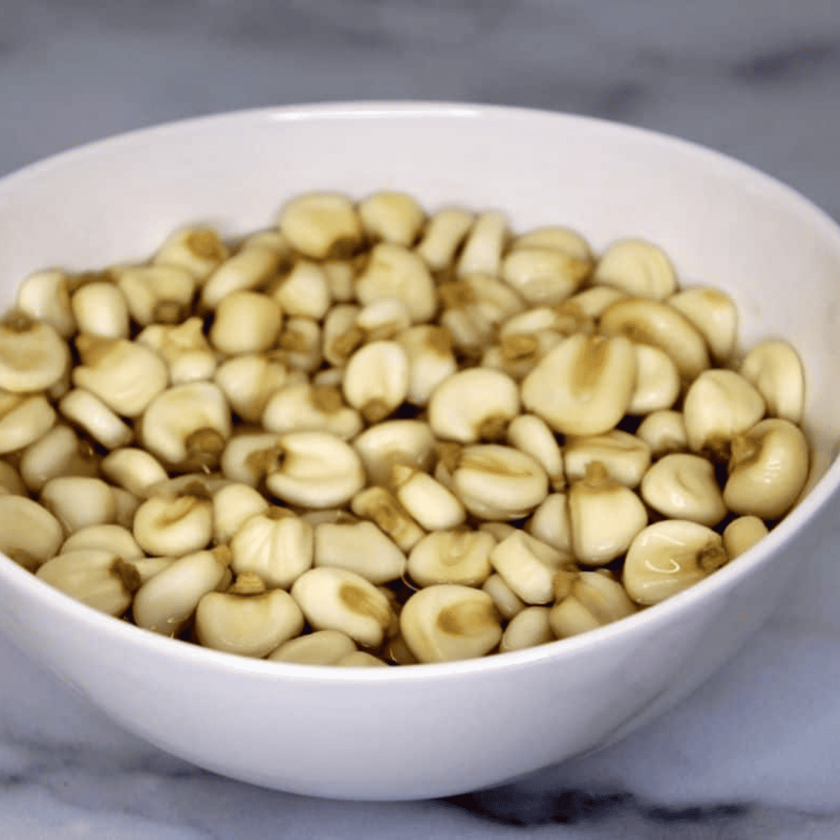 Soaking dried hominy overnight in cold water to soften kernels before air frying corn nuts
