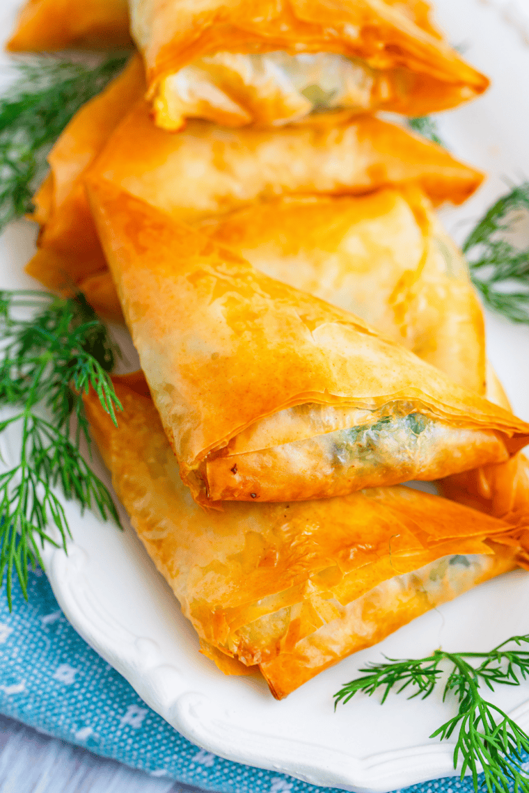 Golden air fryer spanakopita phyllo cups filled with creamy spinach, feta, and ricotta on a serving plate.