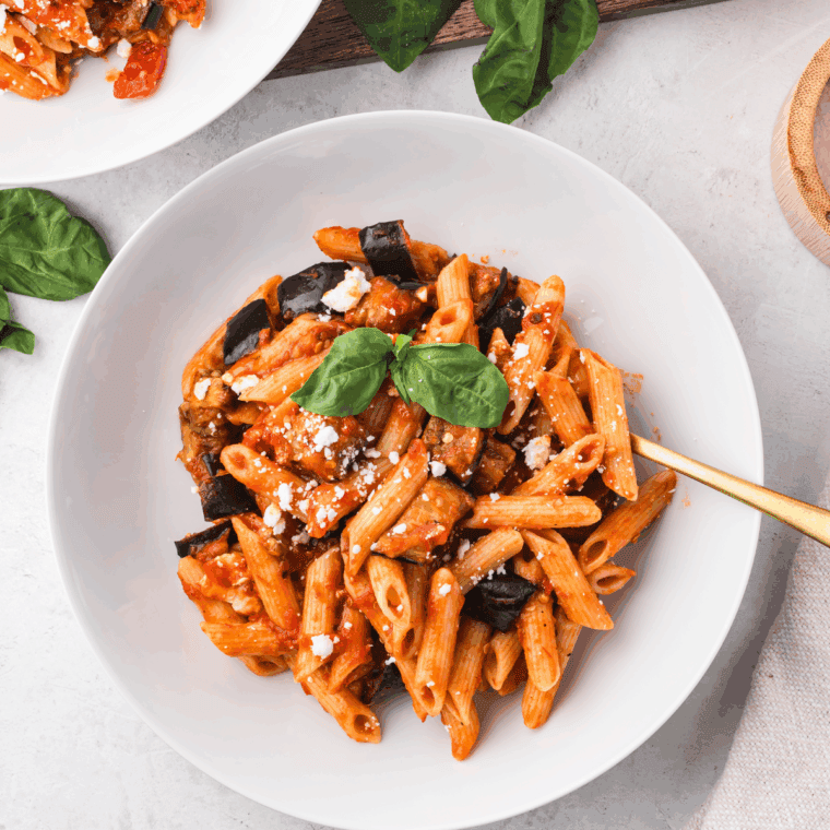 Bowl of homemade Olive Garden-style marinara sauce garnished with fresh basil and served with spaghetti.