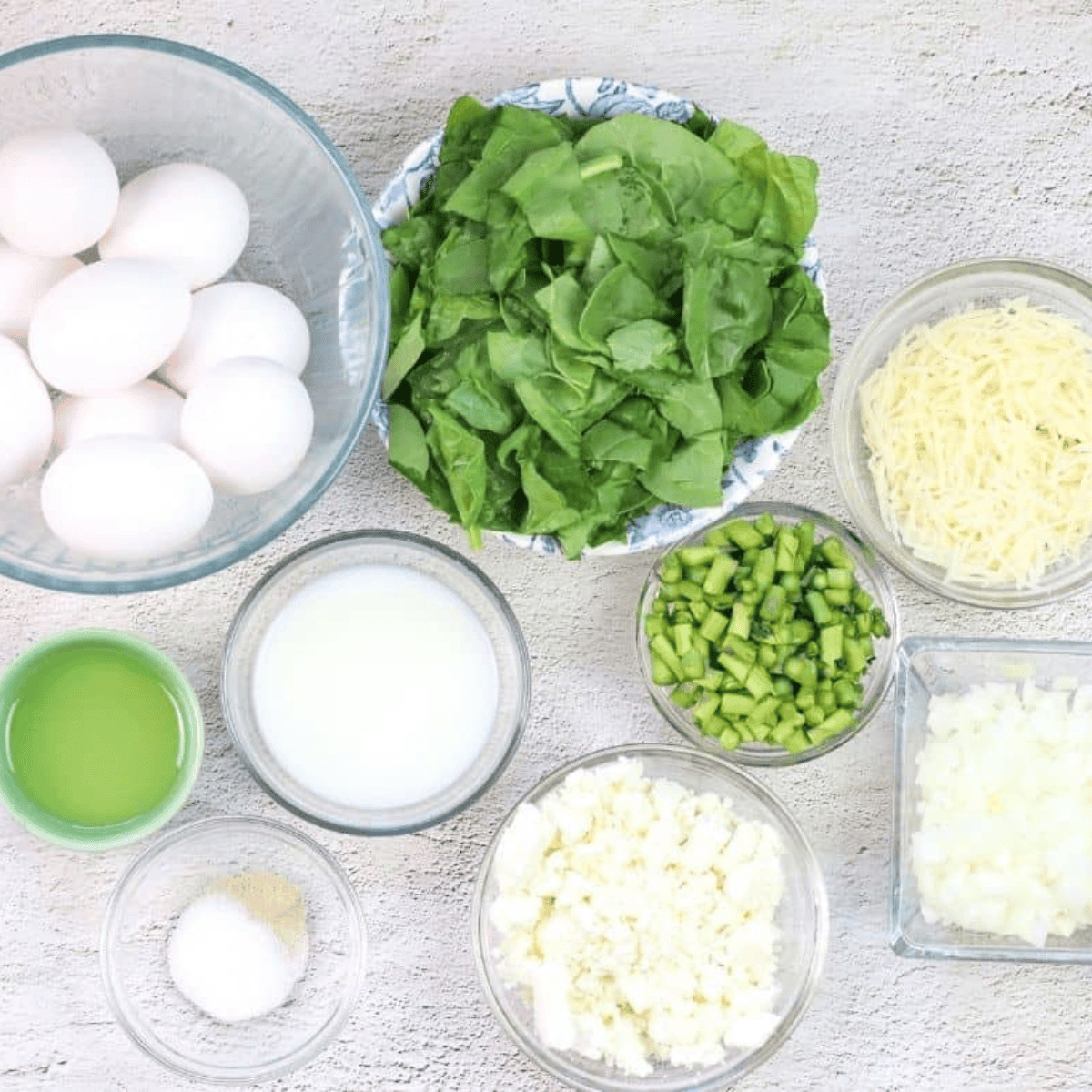 Ingredients needed for Air Fryer Asparagus, Spinach, and Cheese Frittata on kitchen table.