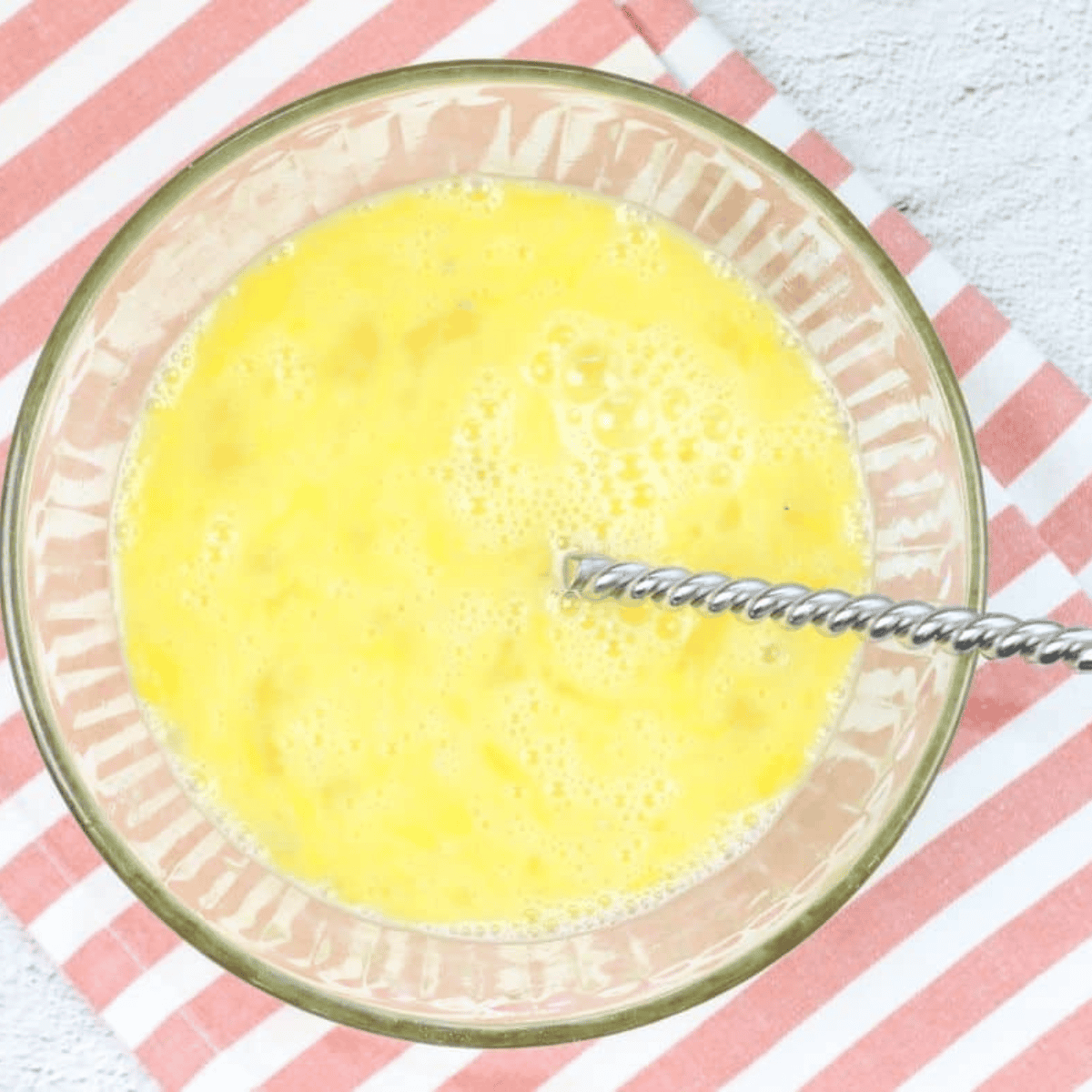 Whisking eggs with milk, salt, and black pepper in a large mixing bowl
