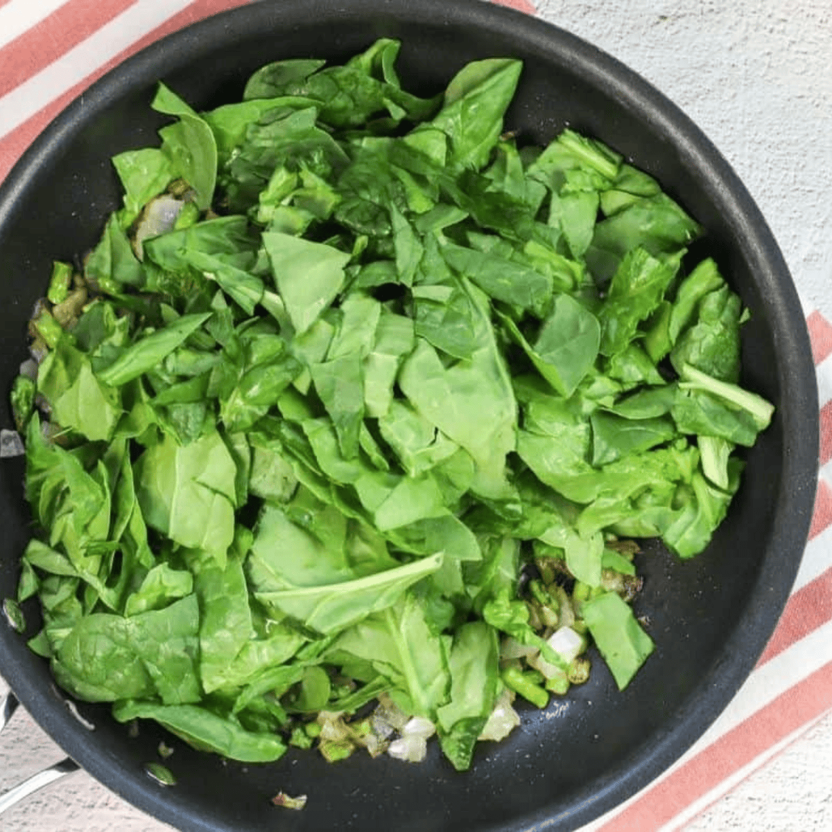 Stirring fresh baby spinach into the skillet until wilted and soft