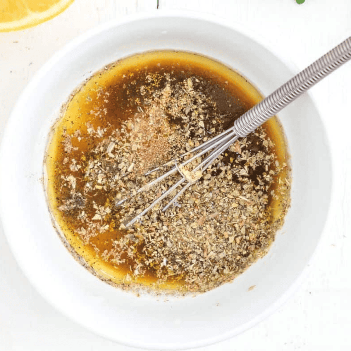 Whisking together lemon juice, olive oil, garlic, and oregano to make the Greek marinade for Air Fryer Chicken Kebabs