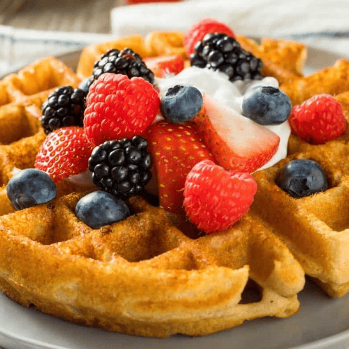 Air Fryer Kodiak Cake Waffles stacked on a plate, golden brown and fluffy, served with syrup and fresh fruit.