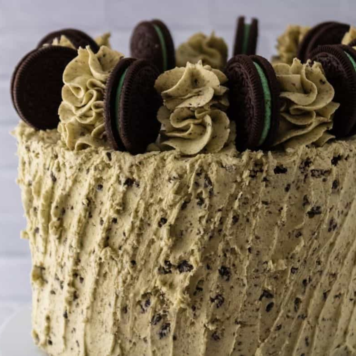 Applying rustic frosting and decorating cake with Mint Oreos and piped buttercream