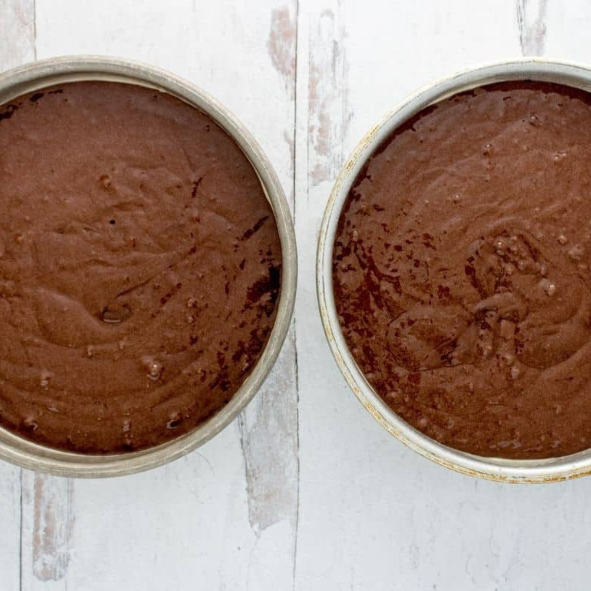 Pouring chocolate cake batter into greased pans before air frying