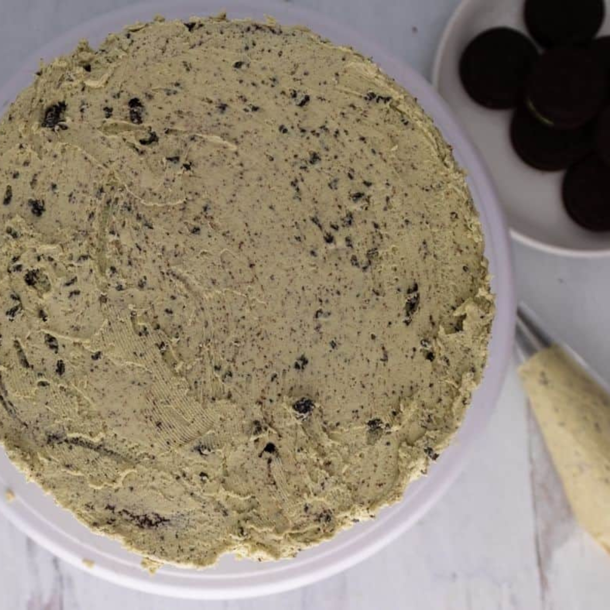 Spreading mint Oreo frosting on first cake layer before adding top layer