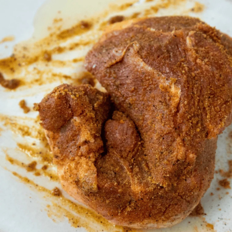 Marinated pork shoulder chunks draining in a colander before going into the air fryer