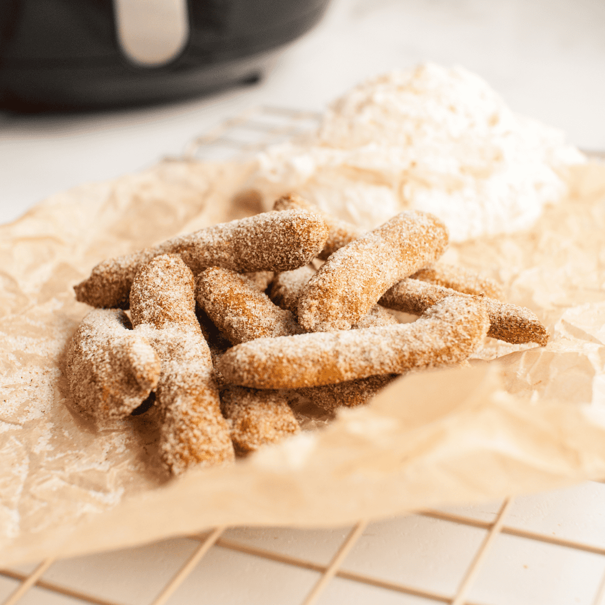 Air Fryer Pumpkin Churros piled on a plate with a bowl of cream cheese frosting dip