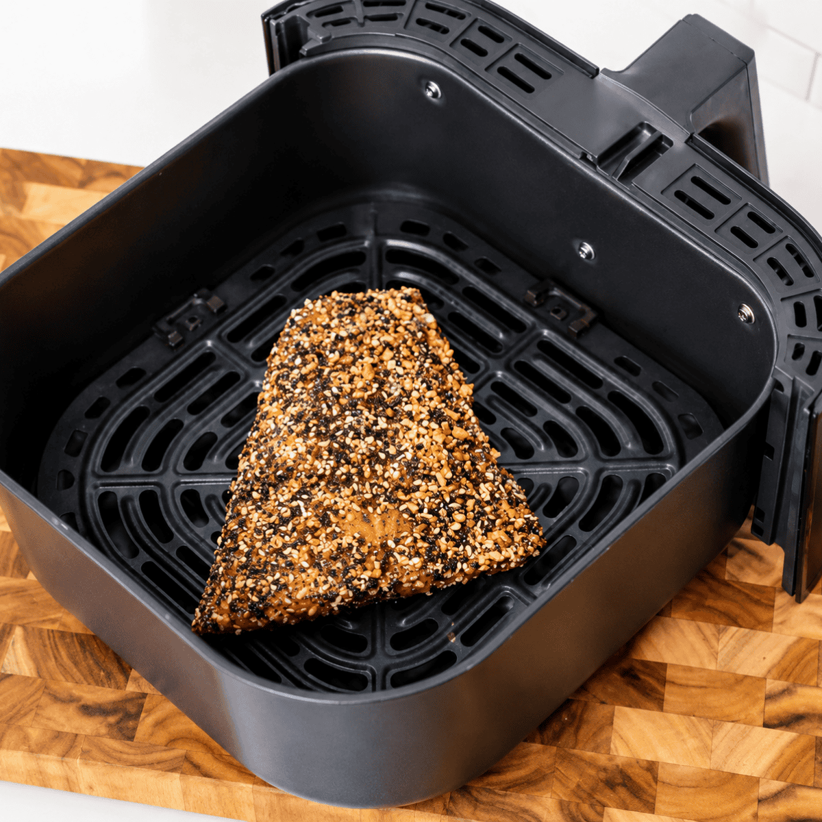 Everything bagel salmon fillets in the air fryer basket before cooking