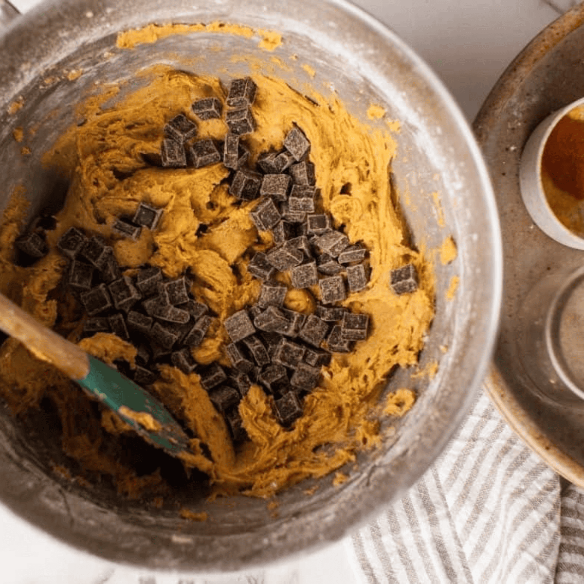 Mixing pumpkin cookie dough with flour, spices, and chocolate chunks until fully combined.