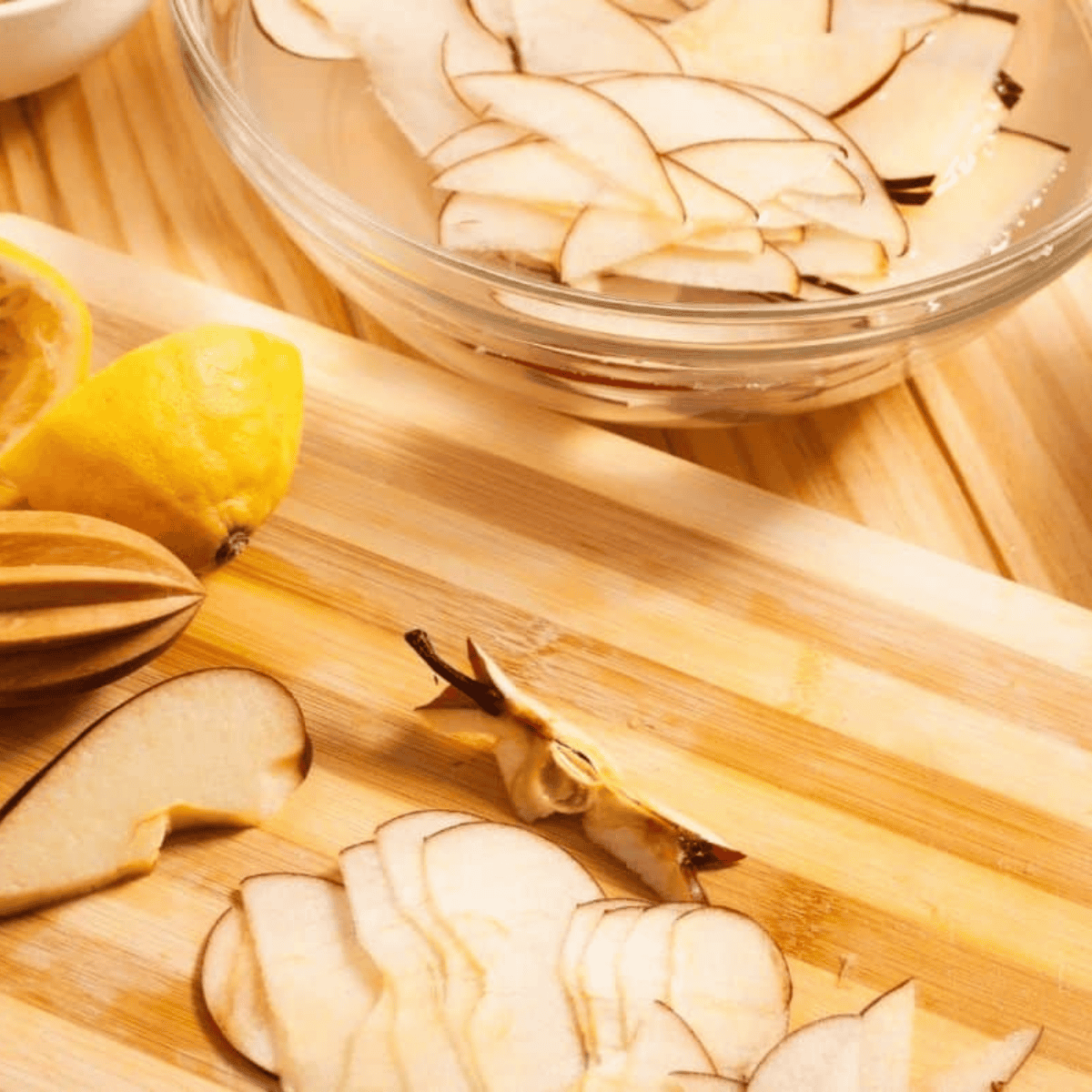Thinly sliced apples soaking in lemon water in a glass bowl