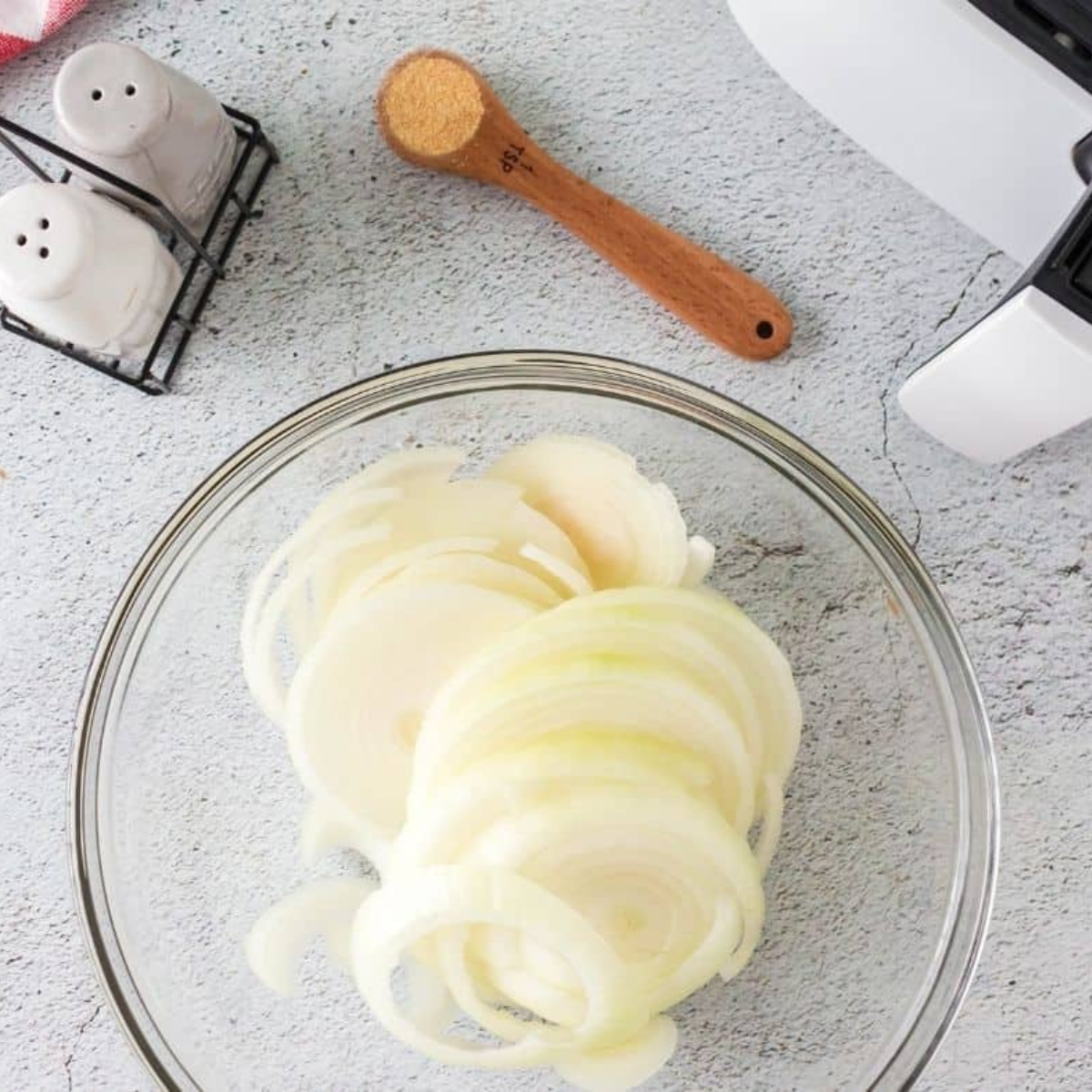 Sweet onion halved and sliced into quarter-inch half-moons on a cutting board