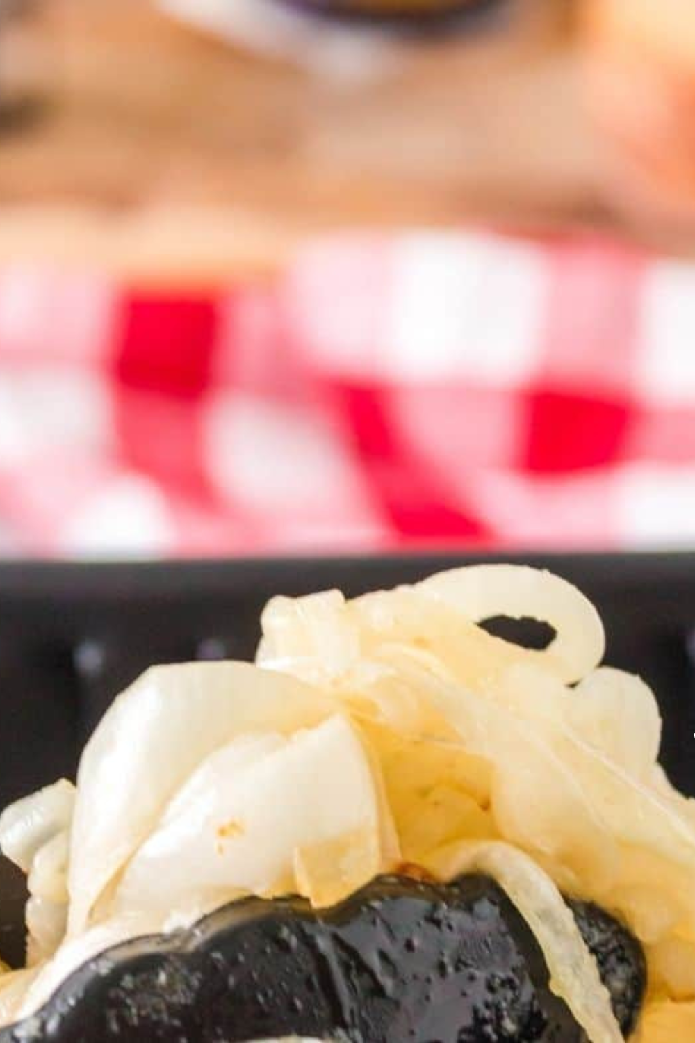 Tongs lifting a pile of soft golden caramelized onions from the air fryer pan